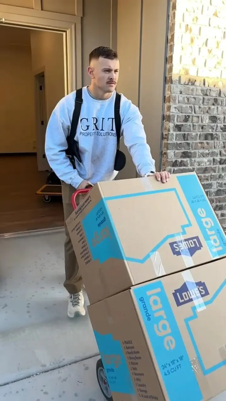 GRIT mover wheeling a stack of large moving boxes on a dolly