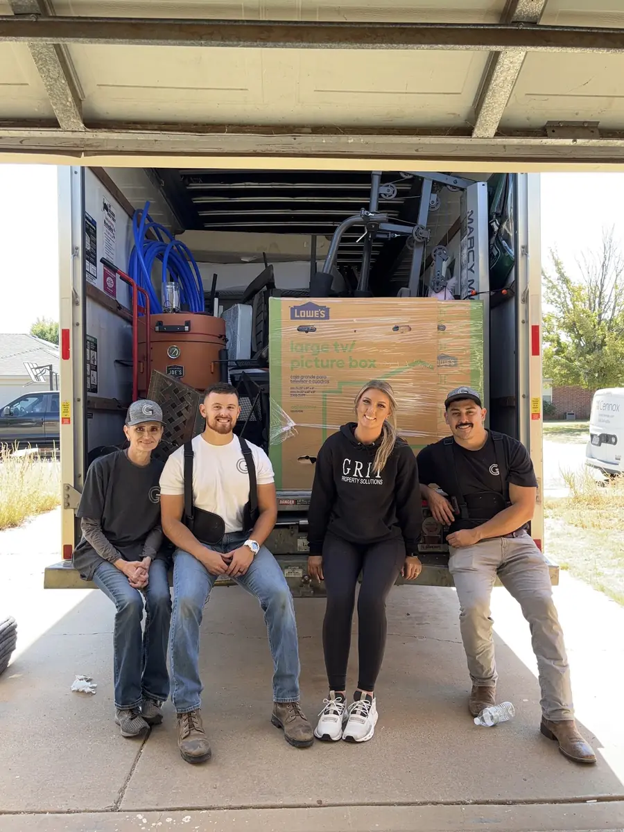 The GRIT Property Solutions crew sitting on the back of a moving truck