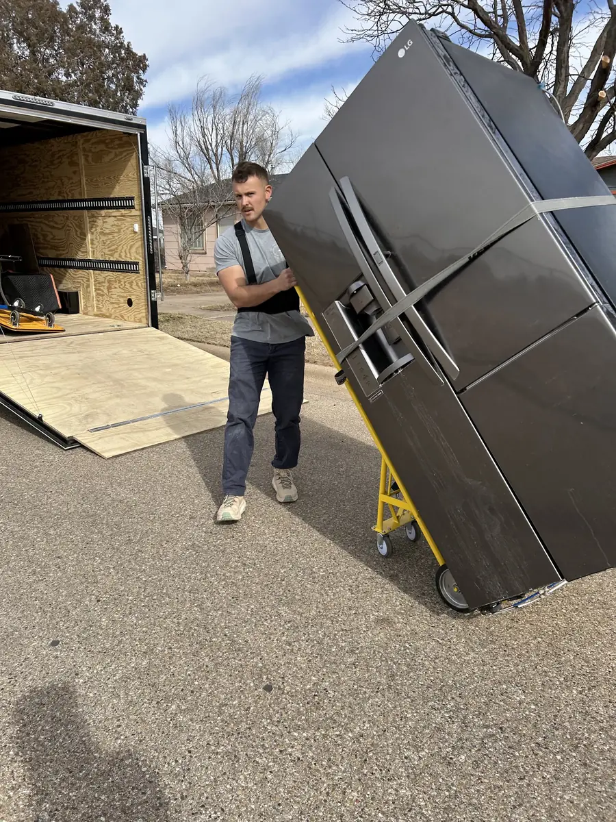 GRIT mover rolling a large refrigerator off a moving truck ramp