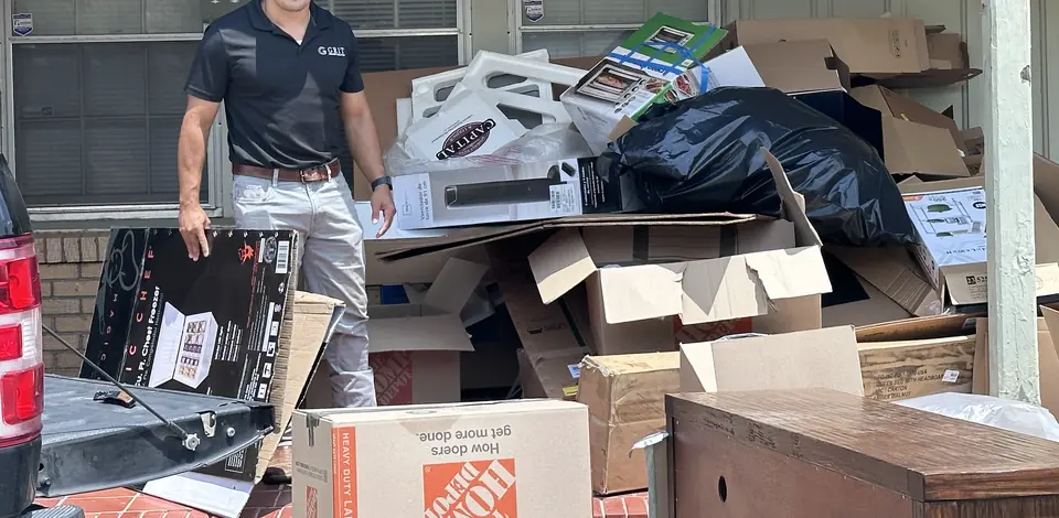 GRIT team member clearing a pile of boxes and household junk from a Lubbock garage