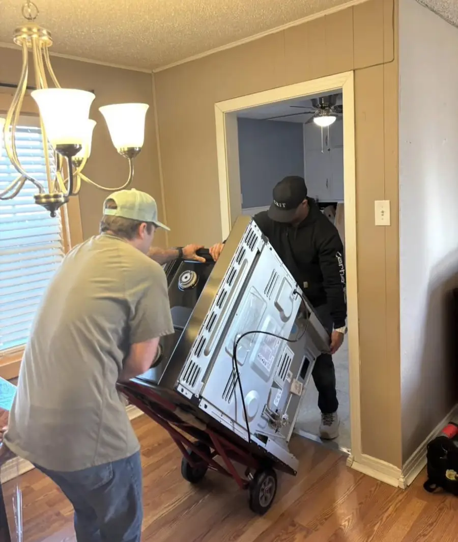 Two GRIT movers carrying a large television through a Lubbock home