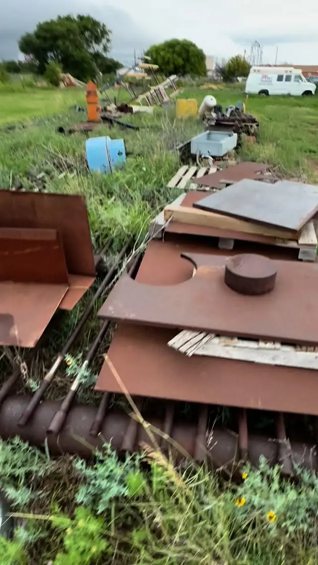 Scrap metal and debris scattered across an overgrown lot before a GRIT cleanup